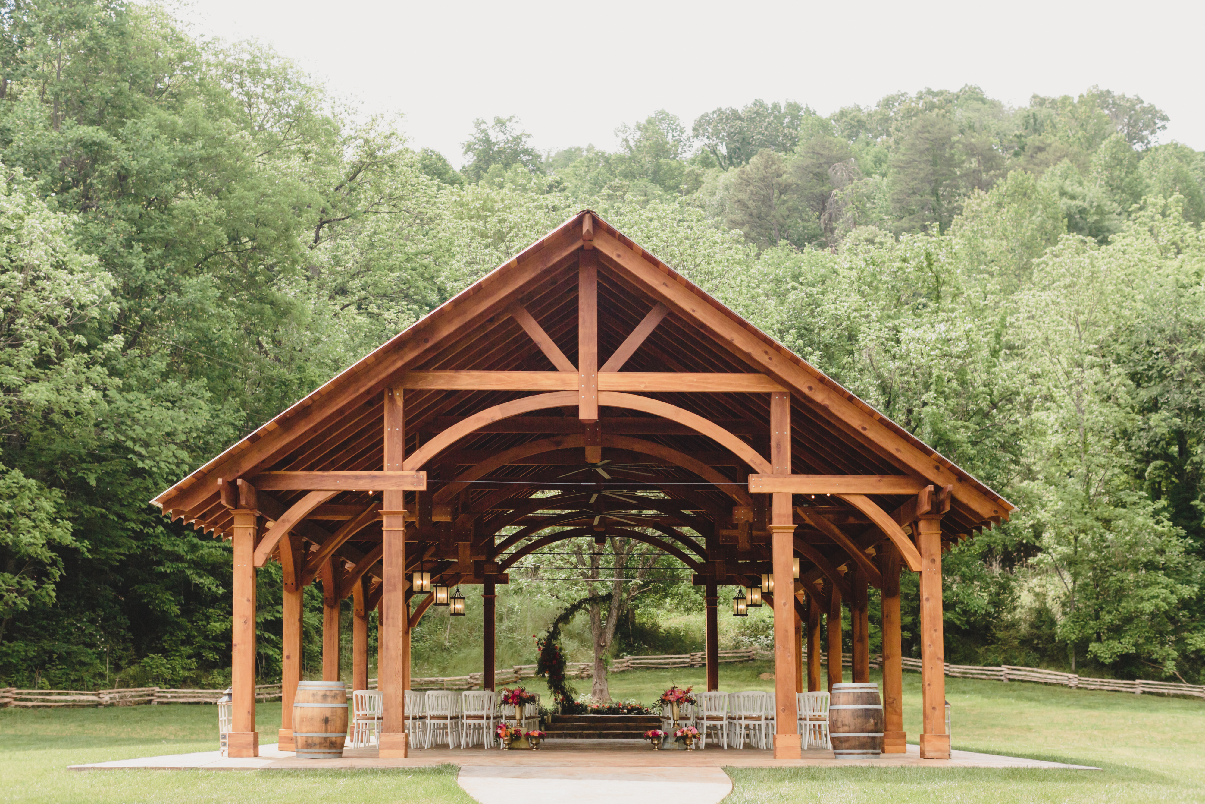 A wooden gazebo in the middle of a grassy field.