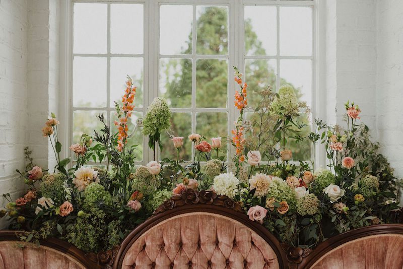 vintage velvet love seat surrounded by natural flowers at The Historic Bleakhouse Venue photographed by Finding Eden Photography || Melissa Timm Designs www.melissatimmdesigns.com